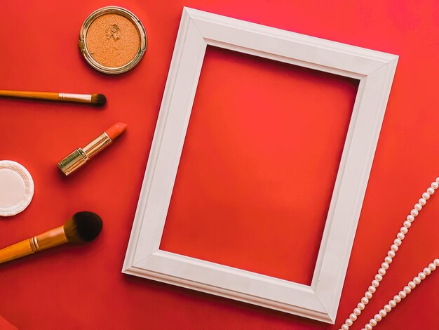 Productos de maquillaje de marco de arte vertical blanco y joyas de perlas sobre fondo naranja como impresión de arte de diseño plano o álbum de fotos