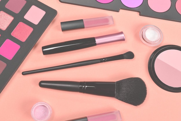 Productos de maquillaje profesional con productos cosméticos de belleza, sombras para ojos, pigmentos, lápices labiales, pinceles y herramientas sobre fondo beige, espacio para texto o diseño.