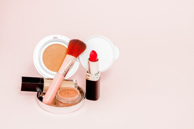 Productos de maquillaje que se derraman en rosa con espacio de copia