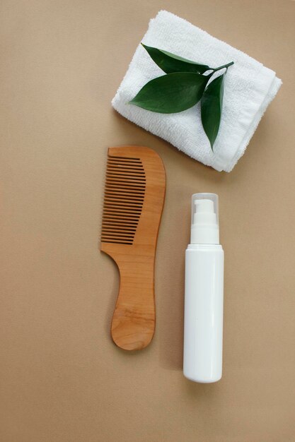 Productos naturales para el cuidado del cabello, cepillo para el cabello, toalla y hojas. vista superior. Champú, mascarilla, bálsamo. plano