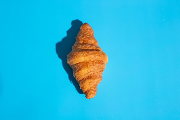Productos de panadería croissant al horno. Fondo azul, vista superior. Estilo pop art. Concepto delicioso y de comida.
