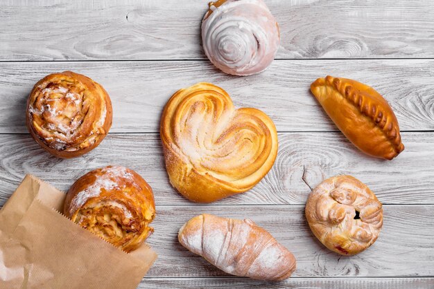 Productos de panadería dulces deliciosos pasteles dorados en mesa de madera.