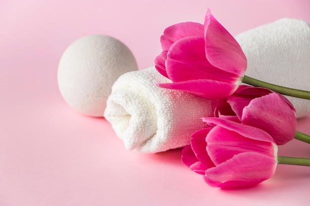 Productos de spa para el cuidado de la piel sobre un fondo rosa. Cosmética natural y tulipanes rojos. Lugar para el texto.