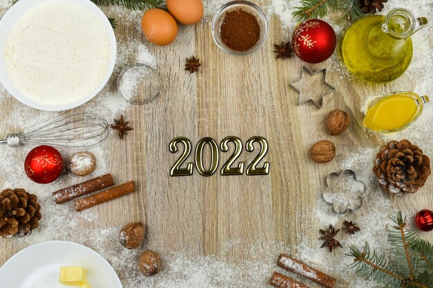 Produkte zum Backen hausgemachter Weihnachtsplätzchen auf Holzuntergrund mit der Aufschrift 2022.