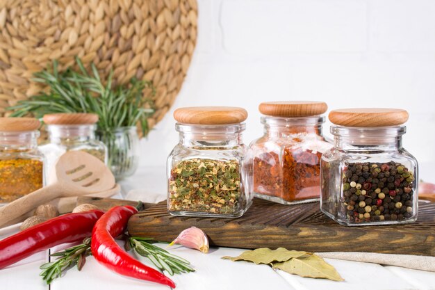 Produkte zum Kochen in der Küche, Küchenutensilien, Kräuter, bunte trockene Gewürze in Gläsern auf weißer Wand