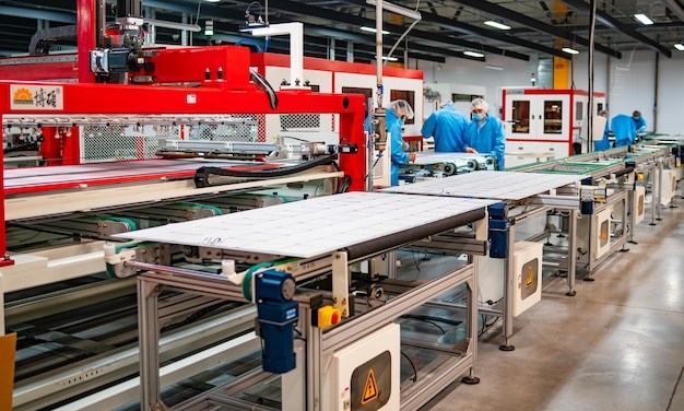 Produktion von Solarmodulen Mann, der in der Fabrik arbeitet Nahaufnahme von Spezialmaschinen in der Fabrik für Solarmodule Industrielle Technik im Werk Moderne grüne Energieerzeugung