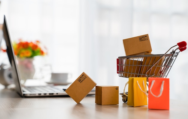 Foto produktverpackungsboxen in wagen und laptop auf schreibtisch