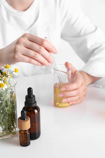 Produto de aromaterapia Cientista desenvolvendo óleos essenciais em mesa branca em laboratório em close-up
