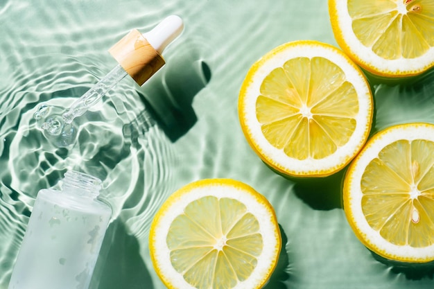 Produto de beleza de soro de soro de pipeta facial perto de limão de frutas cítricas em água espirrando manchas transparentes frescas Antiage