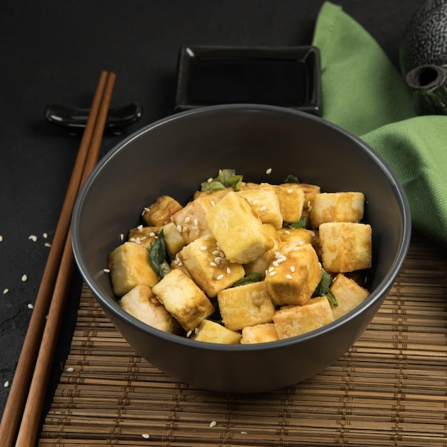 Produto de soja banner de tofu frito em um fundo preto e guardanapo verde proteína alternativa vegan