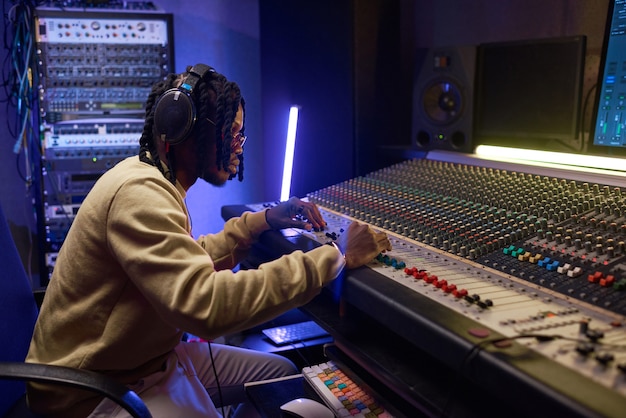 Produtor musical trabalhando na mesa de mixagem em um estúdio de som