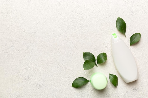 Produtos cosméticos orgânicos com folhas verdes sobre fundo de cimento Copiar espaço plano lay