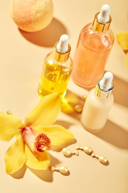 Produtos de cuidados cosméticos em frascos de vidro com óleos de gel creme de soros de flores de orquídea conceito para bem-estar de rosto e corpo e relaxamento tropical spa