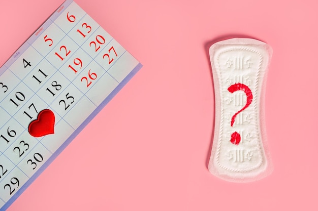 Foto produtos de dias de menstruação coração vermelho e calendário com datas marcadas em vermelho da menstruação em fundo rosa com espaço de cópia foto de alta qualidade