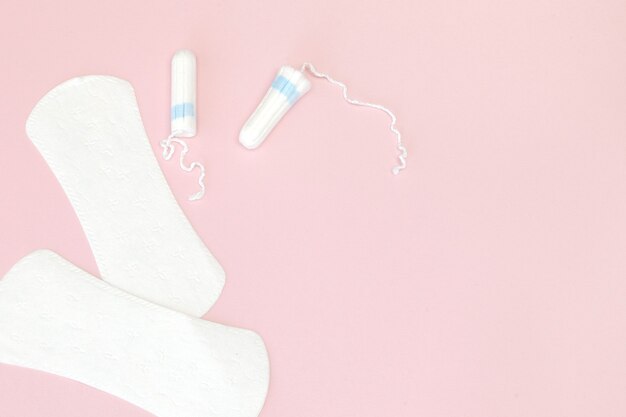 Produtos de higiene íntima para mulheres - absorventes higiênicos e absorventes internos em fundo rosa, copie o espaço.