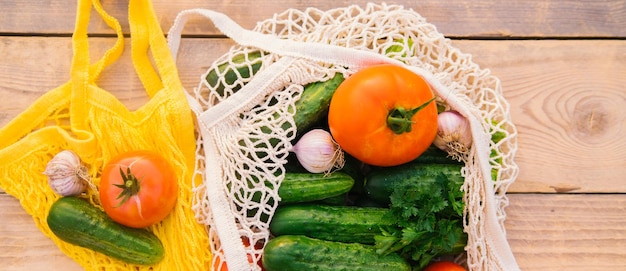 Produtos de legumes frescos e suculentos em um saco de compras reutilizável um saco de corda feito de materiais reciclados em uma mesa de madeira no jardim Vegetarianismo Sem plástico Estilo de vida ecológico