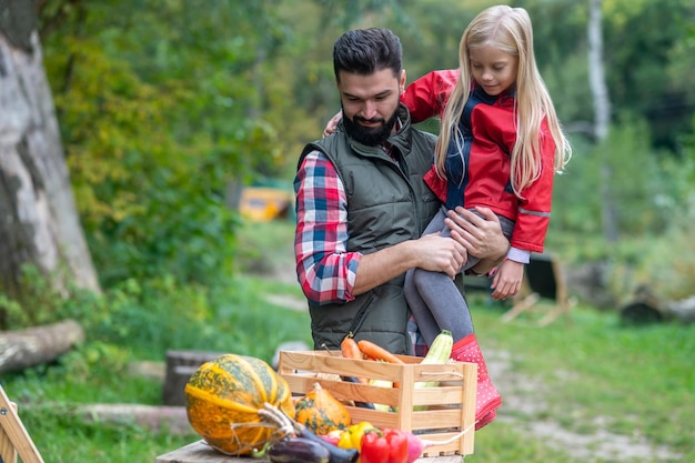 Produtos ecológicos. Pai e filha passando tempo em uma fazenda separando os legumes