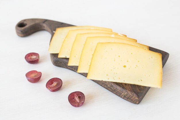 Produtos frescos. queijo fatiado com uvas na mesa rústica.