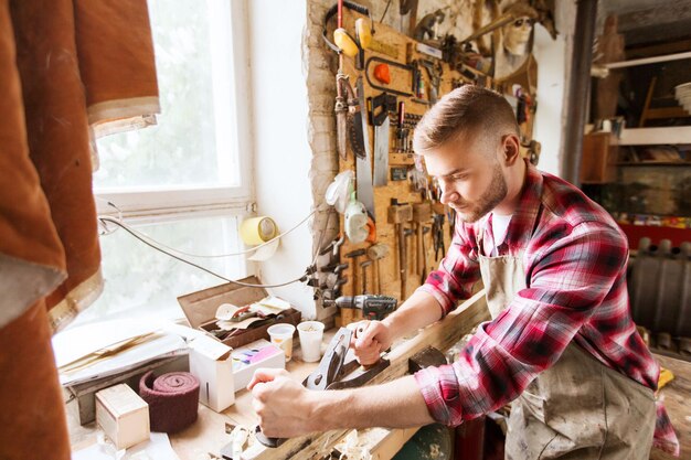 Profesión, carpintería, carpintería y concepto de personas: carpintero que trabaja con planos y tablones de madera en el taller