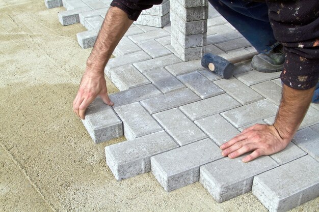 Foto un profesional albañil trabajando en la acera ahorra azulejos