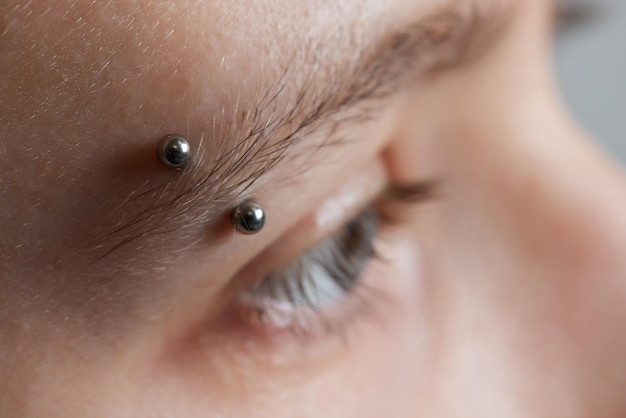 Profesional colocando la joya del piercing en la sien en la cabeza con bola tipo tragus