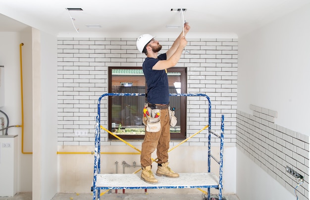 Profesional en monos con herramientas en el sitio de reparación de cuerpo entero. Concepto de renovación del hogar.