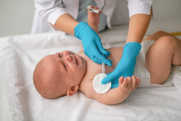 Profesional de la salud inyectando a un bebé en el sofá