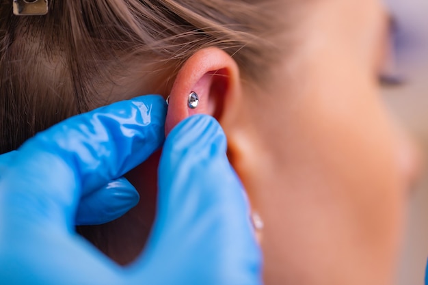 Profesional sosteniendo la joya del piercing justo antes de atornillar la bola