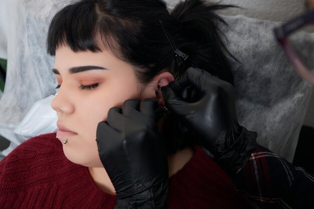 Profesional sujetando la joya del día del piercing justo antes de atornillar la bola. Tipo trago.