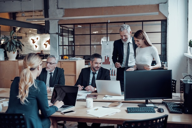 Profesionales del marketing moderno en ropa formal elegante que discuten nuevas ideas de negocios mientras trabajan en la oficina