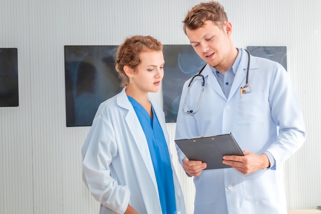 Profesionales de la medicina hombre caucásico con rayos y conversación sobre el paciente con el joven médico.