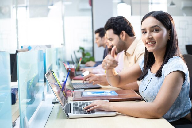 Profesionales mujeres mostrando los pulgares en la oficina
