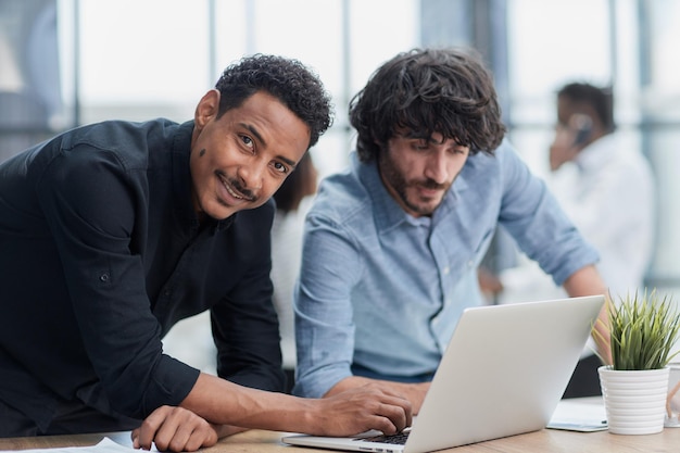 Profesionales de negocios colaborando felizmente en una oficina moderna con tecnología