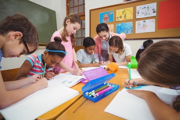 Profesor y alumnos trabajando juntos en el escritorio