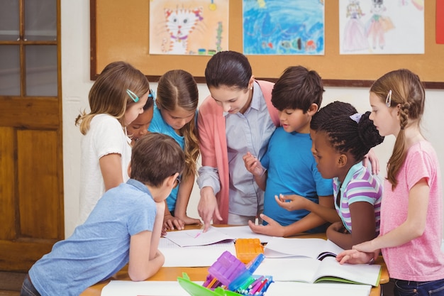 Profesor y alumnos trabajando juntos en el escritorio