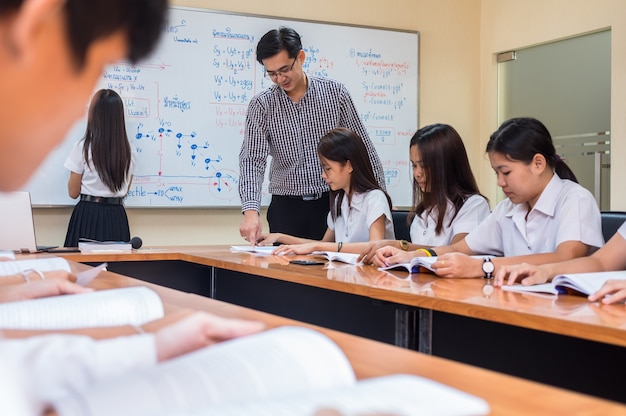 Profesor asiático que da la lección al grupo de estudiantes universitarios en el aula