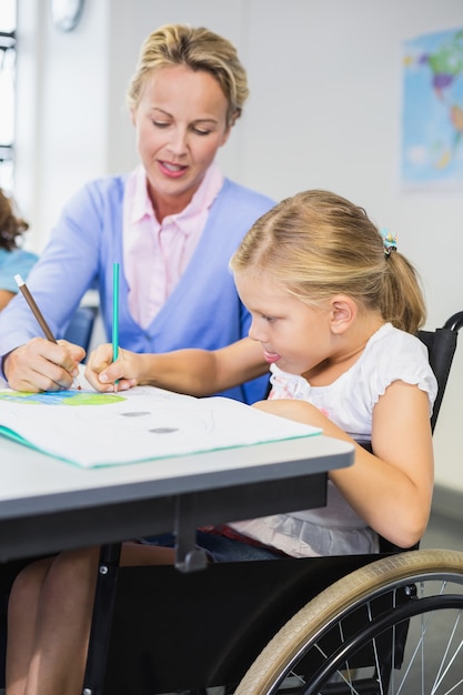 Profesor ayudando a colegiala con su tarea en el aula