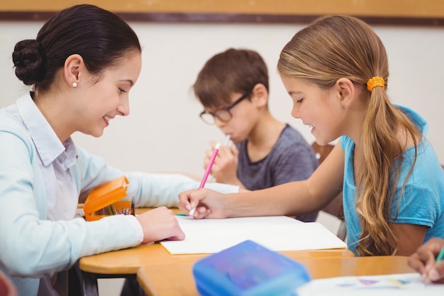 Profesor ayudando a una niña pequeña durante la clase