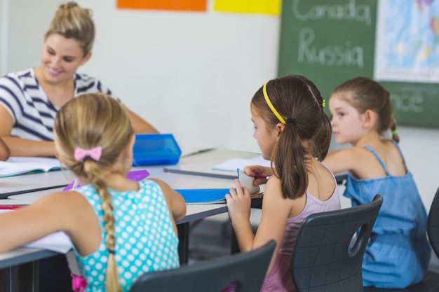 Profesor ayudando a los niños con sus tareas en el aula