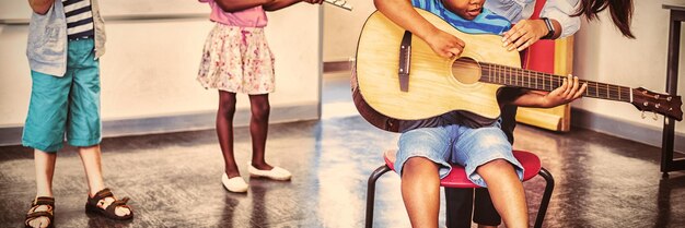 Profesor ayudando a los niños a tocar un instrumento musical en el aula