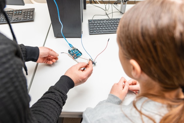 Profesor ayudando a su estudiante adolescente con un robot DIY en la clase de educación del tallo Estudiante después de la clase de codificación de computadoras Construyendo y aprendiendo a programar un vehículo robóticoArduino Instalación ultrasónica