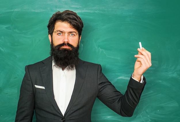 Profesor barbudo en la escuela enseñando en pizarra