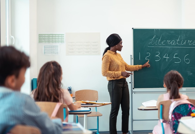 Profesor de cabello oscuro parado cerca de la pizarra