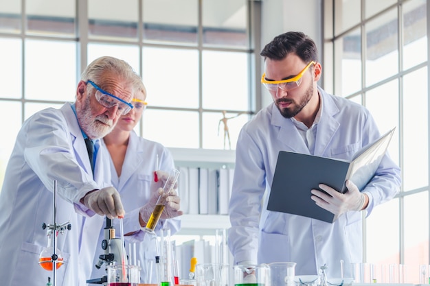 Profesor de ciencias y equipo de estudiantes trabajando con químicos en laboratorio.