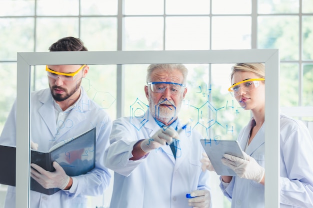 Profesor de ciencias y equipo de estudiantes trabajando con químicos en laboratorio.