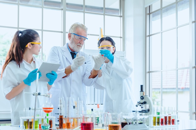 Profesor de ciencias y equipo de estudiantes trabajando con químicos en laboratorio.