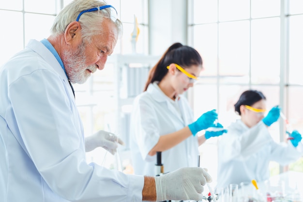 Profesor de ciencias y equipo de estudiantes trabajando con químicos en el laboratorio.