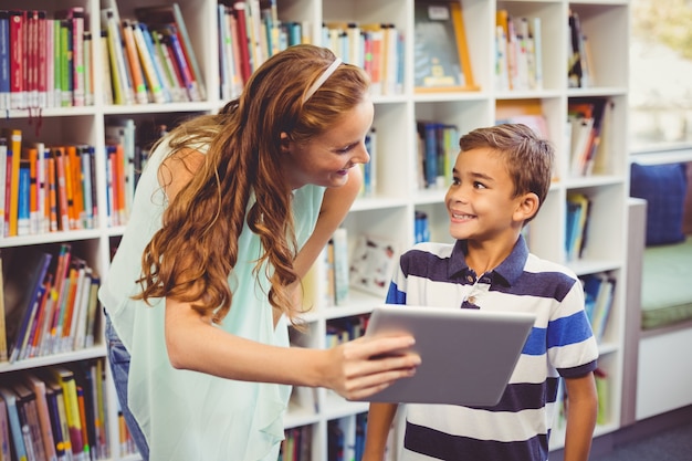 Profesor y colegial con tableta digital en biblioteca