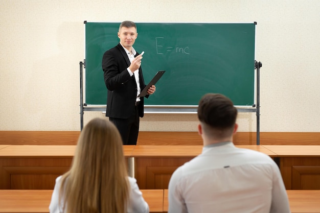 Profesor dando una conferencia en un salón de clases y escribiendo fórmulas matemáticas en la pizarra