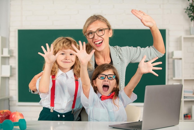 Profesor emocionado con niños de escuela aprendiendo en una computadora portátil estudiando con educación en línea